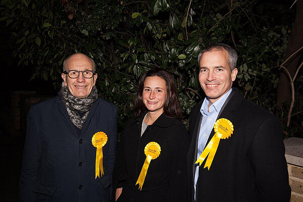 Sarah with two fellow Lib Dems in front of a bush at night